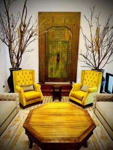 马拉喀什Riad Soir De Marrakech的客厅配有2把黄色椅子和桌子