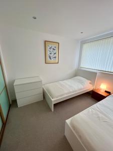 爱丁堡Beautiful modern sea-side apartment in the city的白色的客房设有两张床和窗户。