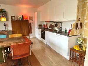 霍森斯2 værelses retro lejlighed på Torvet的厨房配有白色橱柜和木桌