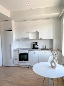 奥卢Studio Apartment Station的白色的厨房配有桌子和白色冰箱