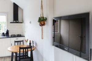 希尔登Huisje Sasa的厨房配有桌子,墙上挂着大电视