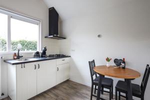 希尔登Huisje Sasa的厨房配有白色橱柜和木桌