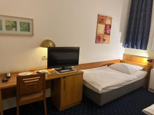 汉堡阿尔托那火车站考梅兹中央酒店的一间卧室配有一张桌子、一张床和一台电脑