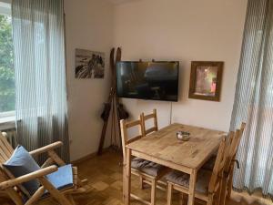 加尔米施-帕滕基兴Apartment Skischanze的一间带木桌和电视的用餐室