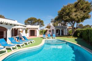 卡拉布兰卡Apartamentos Menorca MONSINES 13C By Mauter Villas的一个带椅子的游泳池以及一座房子