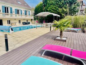 Boissy-lʼAillerieAppartement 120m2 dans maison avec piscine的房屋旁的甲板上设有粉红色和蓝色长凳