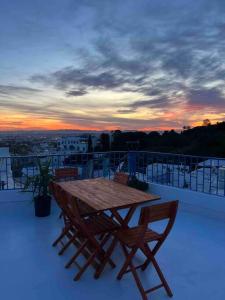 西迪·布·赛义德The Blue Sea View Sidi Bou Said的阳台上的木桌和椅子,享有日落美景