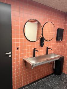 卑尔根City Hostel Bergen的浴室设有水槽和墙上的两面镜子