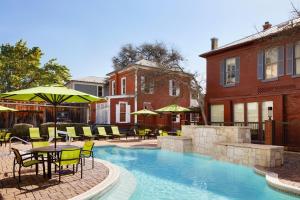 圣安东尼奥圣安东尼奥市中心河滨区春季山丘套房酒店的一个带桌椅和遮阳伞的游泳池