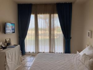 San GiovanniThe Bee House的一间卧室设有大窗户和蓝色窗帘