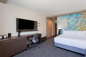 埃尔卡洪圣地亚哥埃尔卡洪万怡酒店 的酒店客房设有一张床、一张书桌和一台电视机。