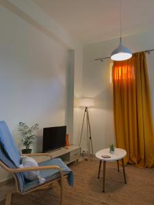 科洛皮奥Helen's cozy studio (close to the airport)的客厅配有桌椅和电视