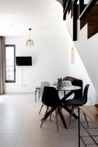 卡拉马塔Pagani Blue - Luxury Maisonette B3的一间拥有白色墙壁和桌椅的用餐室