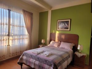 科罗伊科Hostal Kurmi - Coroico的一间卧室设有一张带绿色墙壁和窗户的床。
