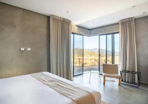 瓜达鲁佩镇Chateaux del Valle Vacational Homes的一间卧室配有一张床、一把椅子和一个大窗户