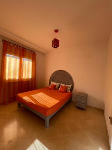 艾尔亚奈Bel appartement à 9 min de l’aéroport的一间卧室配有一张带橙色床罩的床