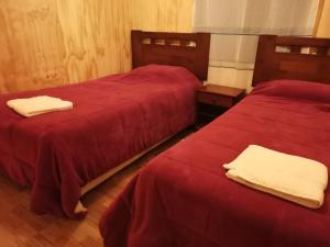洛斯安赫莱斯Cabañas Candelaria的宿舍间的两张床,配有红色床单和白色毛巾