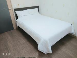 济州市Jeju Olle House的床上铺有白色床单的床