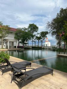 Bagan Jermal2Beds Seaview Straits Quay comes with Carpark and Hothub的一座带两个长椅的游泳池和一座建筑
