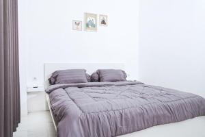 普禾加多Pilla Villa Purwokerto的白色卧室配有一张紫色床单