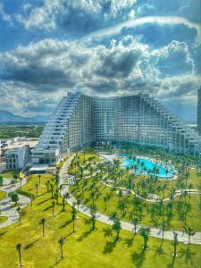 金兰市The Arena Cam Ranh Beach Front的一座带游泳池和棕榈树的大型建筑