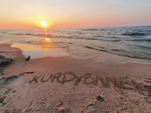 斯蒂格纳Kurdybanek - Domki letniskowe的沙滩上的日落,在沙滩上写着词典