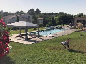 普罗旺斯艾克斯Chalet bois cosy avec piscine Aix nature的坐在游泳池旁带遮阳伞的椅子上的人