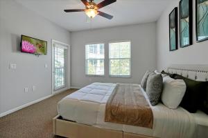 奥兰多Loftly Luxury Modern Oasis 2BR 2BA apartment Windermere FL, near Disney, Universal Studios, Magic Kingdom, Pool, Gym, Patio, free cable, wifi, free parking, gym, Alexa, lake, gated community, spacious closets, close to shops and mall的一间卧室配有一张床和吊扇