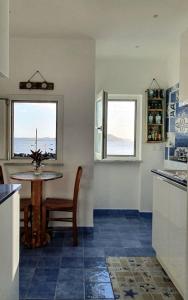 伊斯基亚BeachHouse Ischia的厨房配有桌子和桌子以及2扇窗户。