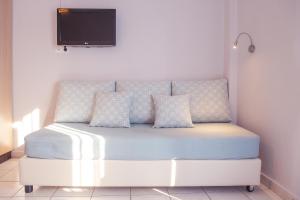 圣加利尼Christof Studios的一张带枕头的白色床和墙上的电视