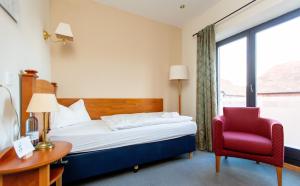 普劳西Hotel und Restaurant Haus Sajons的酒店客房,配有一张床和一张红色椅子