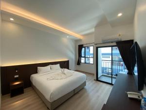 春武里GEEN Hotel Chonburi的一间带白色床的卧室和一个阳台