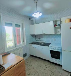 AdaneroChalet de Tony Verde en plena naturaleza的厨房配有白色橱柜、水槽和冰箱。