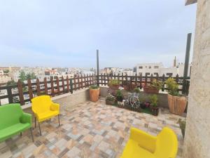 安曼Khalda Rooftop Apt.的大楼内的阳台配有黄色和绿色椅子
