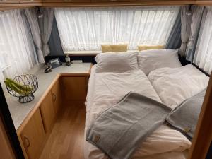 韦斯特曼纳埃亚尔Cozy Caravan的小客房内的一张床位,配有白色床单和枕头