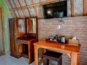 KlungkungMertha Sari Resto & Bungalow的客房设有木桌和墙上的电视。