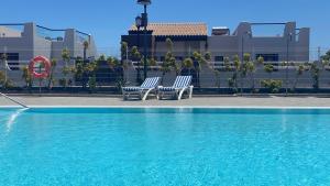 卡勒达德福斯特Sunny Luxury Apartment with two-level terrace, two swimming pools, next to golf course的两把蓝色椅子坐在游泳池旁