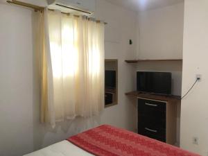 伊塔帕里卡Pousada Ponta de Areia的一间卧室设有一张床、一台电视和一个窗口。