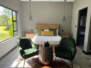 伯诺尼Swan Lake Suites的一间卧室配有一张床和两张绿色椅子