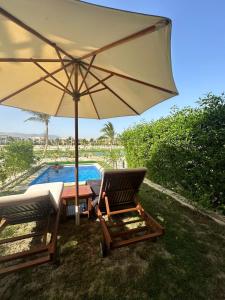 Ma‘mūrahHawana Salalah luxury 1BR TH with private pool的游泳池旁的两把椅子和一把遮阳伞