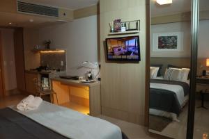 巴西利亚Flat Premium Particular Cullinan Hotel的酒店客房带一张床、一张书桌和一面镜子