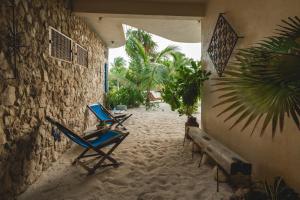 埃尔库约Casa Mia El Cuyo Eco Beach Boutique Hotel的几把椅子坐在建筑物旁边的沙子上
