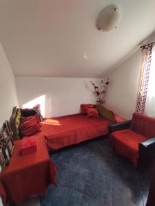 巴尔Apartmani Nikola的客厅配有红色的沙发和2张红色的桌子