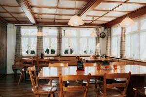 Gais盖斯克隆酒店的餐厅设有木桌、椅子和窗户。
