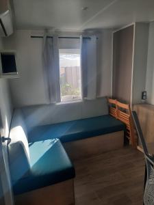 纳博讷Mobil-home premium 325的小房间设有蓝色的沙发和窗户