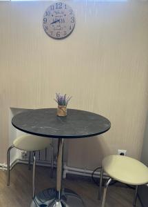 塞凡Brand new comfortable apartments in Sevan city的一张桌子、两把椅子和墙上的时钟