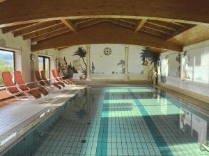 茨维泽尔Hotel Sonnenhof - Superior的一个带椅子的室内游泳池和瓷砖地板
