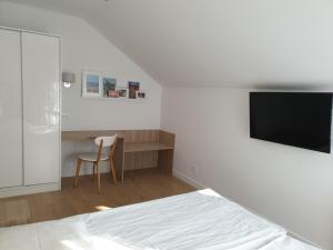 格但斯克Messina Apartamenty Wyspa Sobieszewska的一间卧室配有一张床、一张书桌和一台电视。