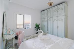 亚历山大Nabeel Homes - Seaview Condo - SP的白色卧室,配有一张带天鹅的床