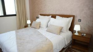 TaounateHotel Riad Taounate的一间卧室配有一张带两盏灯的大型白色床。